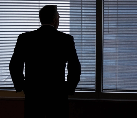A Engenharia do Re-framing na Liderança Executiva A Armadilha da Defesa: Por Que Justificativas Validam o Tribunal Alheio
Quando um comitê executivo internacional contesta as diretrizes de um projeto de expansão, o reflexo mais recorrente dos líderes é recuar para a trincheira das justificativas operacionais. Apresentam-se planilhas adicionais, argumenta-se a urgência dos cronogramas e tenta-se demonstrar que o investimento “não é tão dispendioso” quanto parece.
No entanto, no âmbito da diplomacia corporativa avançada, quem se justifica valida o tribunal do outro.
Ao aceitar debater exclusivamente sob o enquadramento de “gasto arriscado”, o executivo assume voluntariamente o papel de réu perante o conselho. Como demonstra a Teoria do Enquadramento (Framing Theory) do sociólogo Erving Goffman, a definição da realidade em uma interação social pertence a quem estabelece a moldura interpretativa. Dados técnicos, por mais consistentes que sejam, tornam-se inócuos se forem apresentados dentro de premissas construídas para limitá-los.
Lideranças maduras em fóruns globais não reagem a ataques com contra-argumentos apressados; desconstroem a premissa do interlocutor antes de expor qualquer dado substantivo.
O Protocolo Luminary: A Engenharia do Re-framing em 3 Movimentos
Para transferir conceitos sociológicos de poder e interação para a prática linguística sob alta pressão, a The Luminary Learning Academy estruturou um framework retórico tripartite para fóruns internacionais:
1. Neutralização Tática (Tactical Acknowledgment) O primeiro movimento busca desarmar a agressividade da sala sem conceder terreno conceitual. Em vez de confrontar o conselheiro de imediato — gerando atrito desnecessário — ou pedir desculpas pelo investimento — sinalizando fraqueza —, o líder valida a responsabilidade fiduciária da mesa: "I fully share the committee’s mandate to safeguard operating margins this quarter..." Ao expressar alinhamento com a salvaguarda das margens operacionais, os escudos defensivos dos interlocutores são neutralizados, abrindo espaço para a receptividade intelectual.
2. Deslocamento de Eixo (The Linguistic Pivot) O segundo movimento recorre a conectivos diplomáticos refinados para drenar o valor da discussão periférica e conduzir o comitê para o verdadeiro dilema estratégico: "However, the strategic metric here isn’t immediate overhead, but market share defense..." O pivô linguístico reposiciona o debate: a discussão deixa de ser sobre despesa corrente e passa a ser sobre sustentabilidade competitiva de mercado.
3. Imposição da Nova Moldura (The New Frame) No terceiro movimento, estabelece-se a métrica soberana que rege a deliberação. Introduz-se o conceito analítico do custo de inação (cost of inaction), convertendo a proposta em uma resolução imperativa de governança: "When viewed through the cost of inaction, postponing this footprint multiplies our customer acquisition cost threefold by Q4." Sob essa nova régua, adiar o projeto deixa de ser uma decisão prudente de corte de custos e revela-se como um passivo financeiro crítico para os trimestres seguintes.
Estudo de Caso Retórico: A Mudança de Script em Tempo Real
A diferença entre o executivo funcional e o articulador estratégico manifesta-se com clareza na gestão das pressões orçamentárias:
A Provocação da Mesa (Moldura de Custo Imediato): "Your LatAm expansion budget is too expensive for this fiscal year."
A Reação Comum (Defensiva e Vulnerável): "I know it’s expensive, but if we don’t spend this, we will lose future revenue." Diagnóstico: O profissional admite o custo excessivo ("I know it’s expensive") e projeta um cenário hipotético frágil sem ancoragem em indicadores concretos.
A Execução Retórica Luminary (Controle de Moldura e Autoridade): "I fully share the committee’s mandate to safeguard operating margins this quarter. However, the strategic metric here isn’t immediate overhead, but market share defense. When viewed through the cost of inaction, postponing this footprint multiplies our customer acquisition cost threefold by Q4." Diagnóstico: A objeção inicial é absorvida com elegância, o eixo de análise é redirecionado para métricas de sobrevivência competitiva e a inação é demonstrada como o risco financeiro primordial.
Da Fluência Instrumental ao Poder Decisório
A comunicação corporativa perante boards e matrizes internacionais não constitui uma prova de vocabulário passivo ou domínio estrito de gramática escolar. Trata-se de arquitetura deliberada de poder e influência decisória.
A fluência convencional ensina o profissional a traduzir ideias; a The Luminary Learning Academy treina executivos e C-Levels para governarem a mesa de deliberação. Capacitamos lideranças seniores para que o inglês corporativo funcione como um ativo de persuasão, diplomacia e autoridade incontestável nos fóruns mais disputados do mercado global.
Sua autoridade estratégica não deve ser enfraquecida por barreiras de articulação linguística.